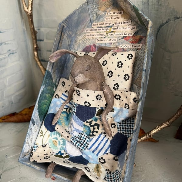 Paper mache sleeping hare under handmade quilt