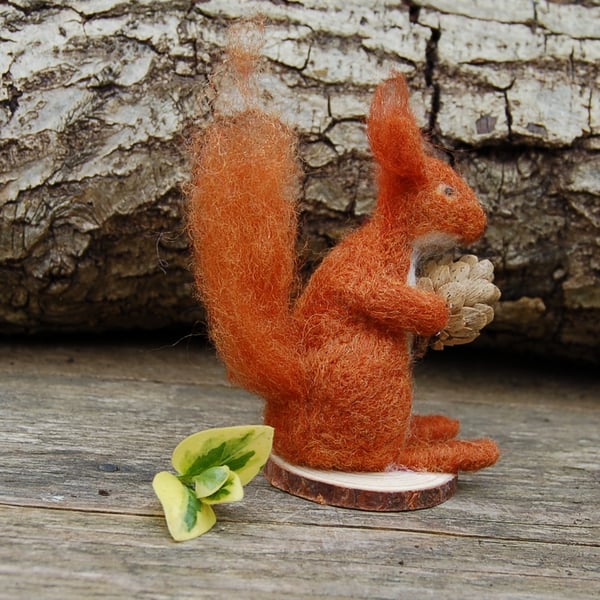Needle felt red squirrel holding a pine cone