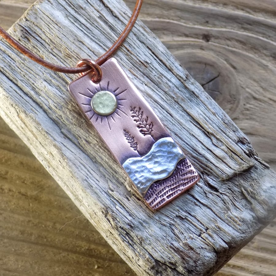 Copper and silver 'winter sun' mixed metals scene pendant