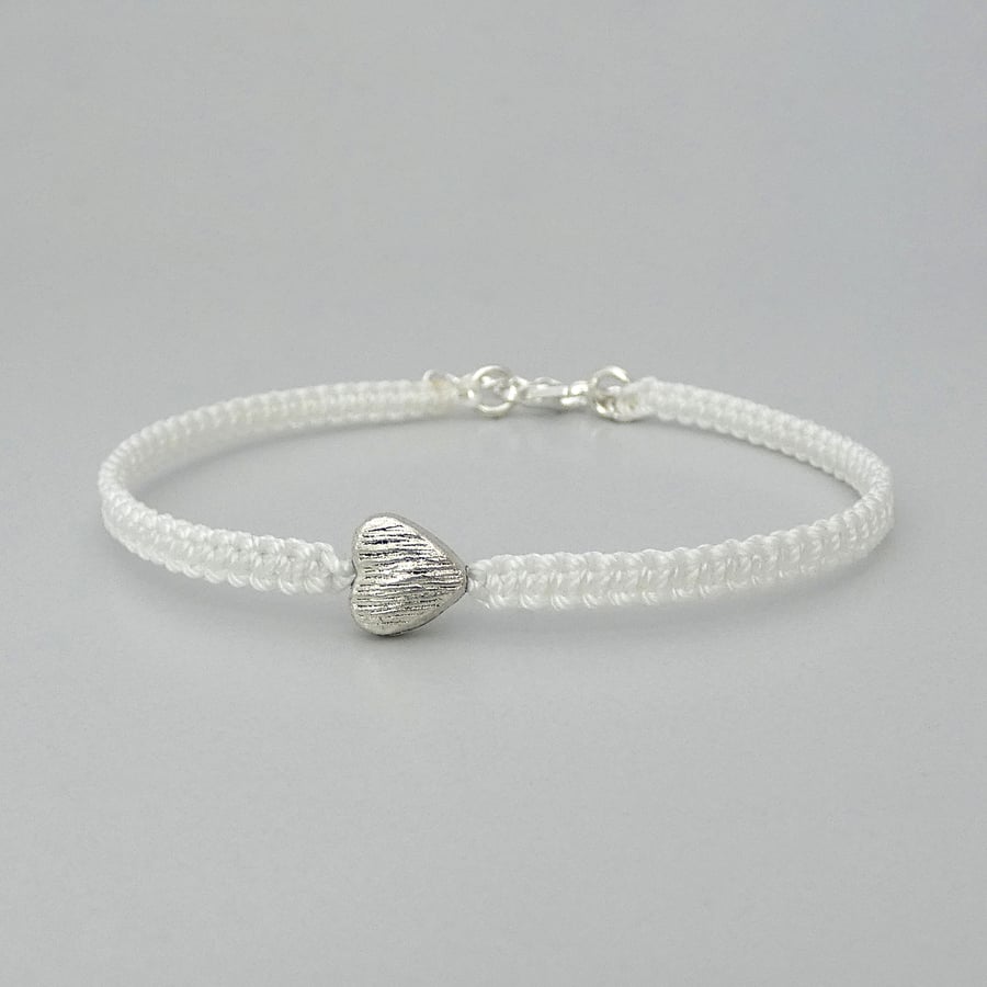 White 7" macrame bracelet with silver plated heart charm and 1” extender chain. 