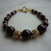 AUBERGINE AND GOLD PLATED RHINESTONE BALL BRACELET.  375