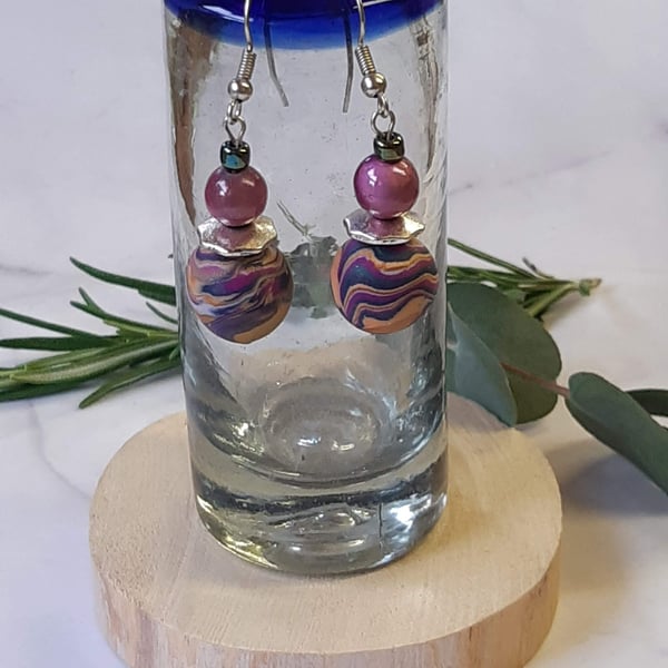 Handmade dangly polymer clay earrings in a colourful swirl design