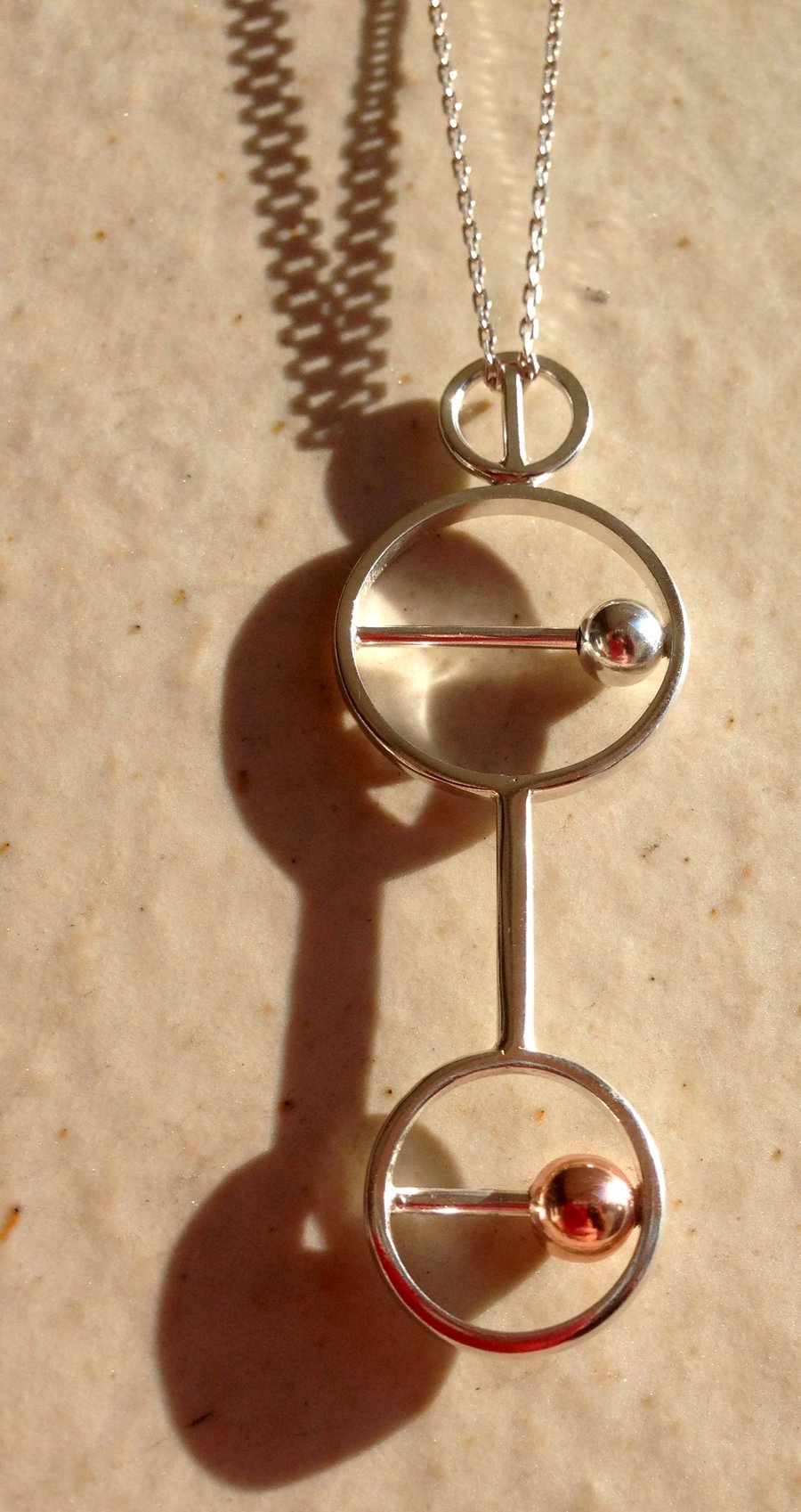 A statement kinetic pendant in Sterling silver with silver and copper beads