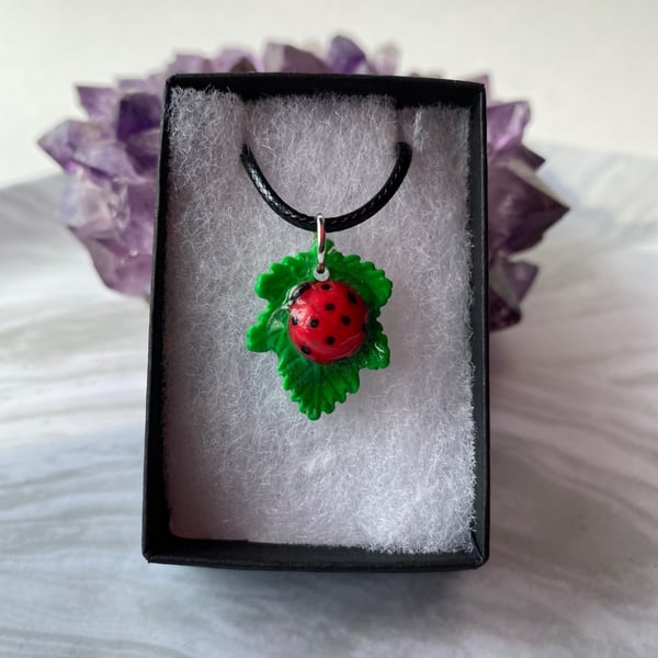 Ladybird and leaf necklace hand painted polymer clay and resin with black cord.