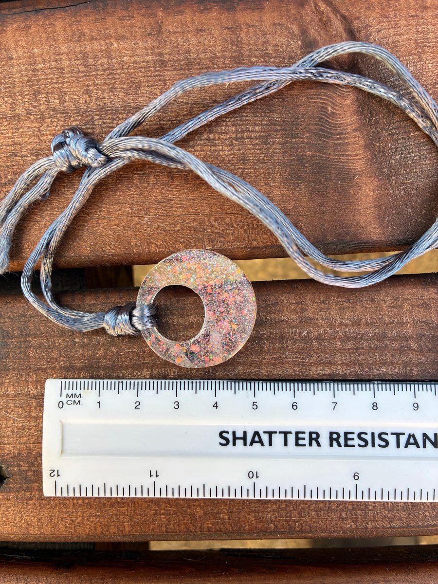 Circular sparkly resin pendant with pink holographic glitter