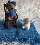 Teddy sitting in a rocking chair on a mat with her cat