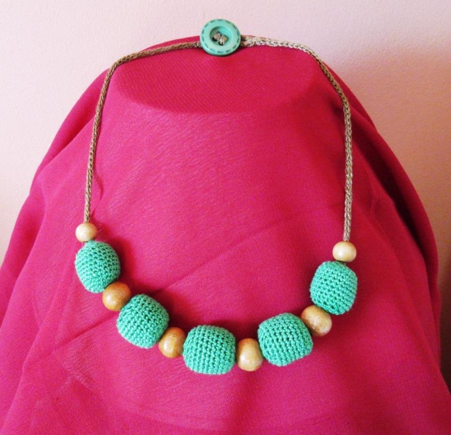 A necklace of 5 crocheted beads with wooden bead spacers on a knitted i-cord