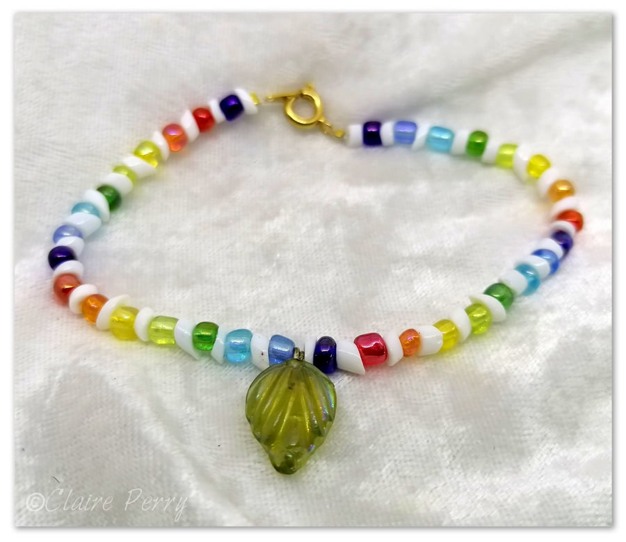 Seed bead bracelet with rainbow coloured glass beads with a green glass charm.