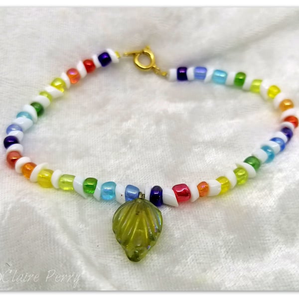 Seed bead bracelet with rainbow coloured glass beads with a green glass charm.