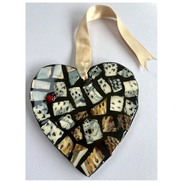 A heart shaped mosaic pendant with a snowy owl and thrush theme. 