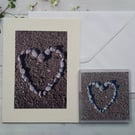 Photo of pebbles in a  heart shape on a beach. An A5 card with a coaster.