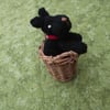 Knitted black dog in a basket