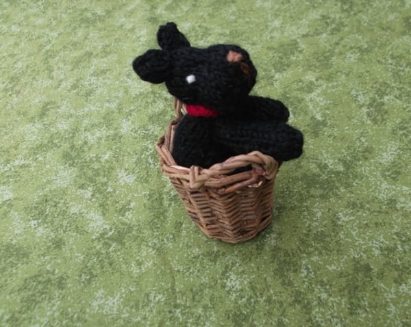 Knitted black dog in a basket