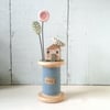 Little oak house with clay flower and bird on wooden bobbin