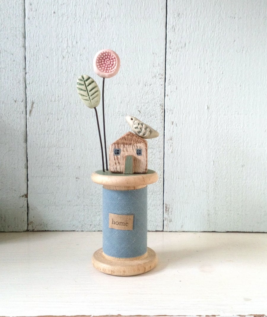 Little oak house with clay flower and bird on wooden bobbin