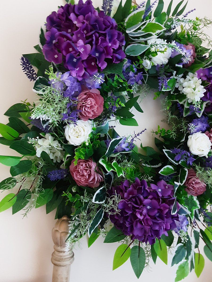 Kate. Large wreath, purples, white and green. Door, wall , bedroom. 