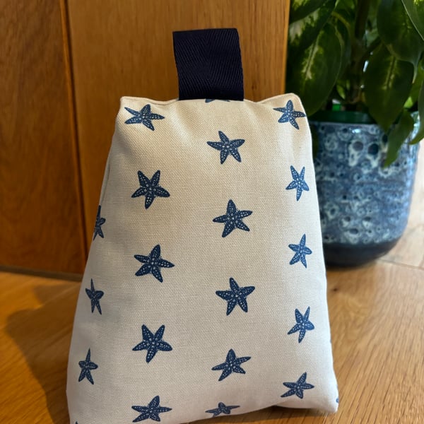 Cotton fabric doorstop in taupe with navy starfish print, filled with pebbles.