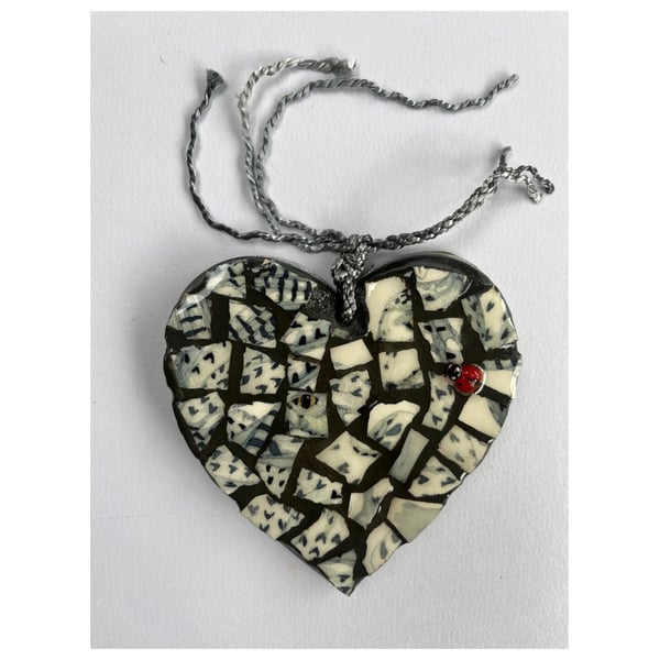 A heart shaped pendant with grey, black, and white ceramics.