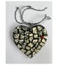 A heart shaped pendant with grey, black, and white ceramics.