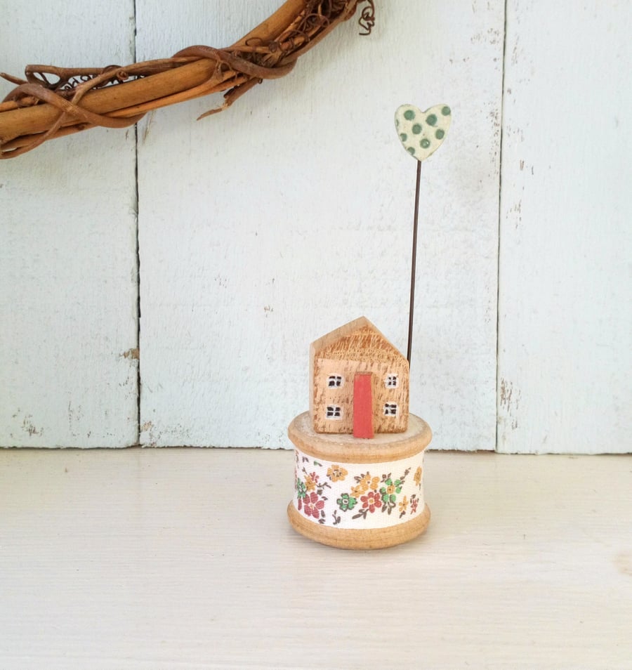 Little wooden house with clay heart on vintage bobbin