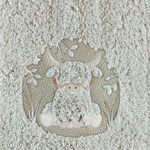 Adorable highland cow embossed on a light brown hand towel