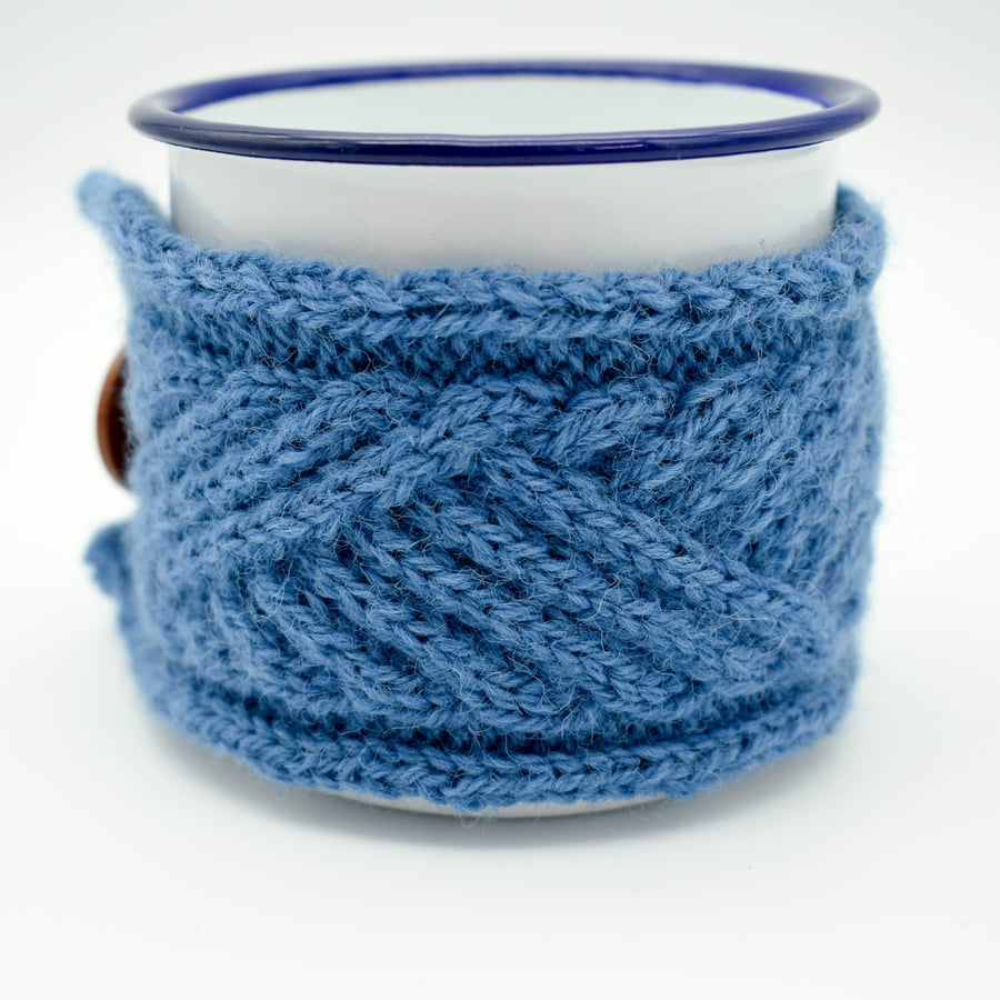 White enamel camping mug with hand knitted mug cosy in blue