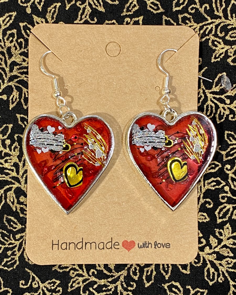 Silver Framed Heart Shaped Drop Earrings With Gold And White Hearts On Red 