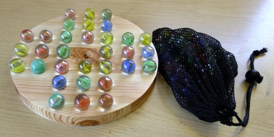 Solitaire marble game for children & adults on wooden board.