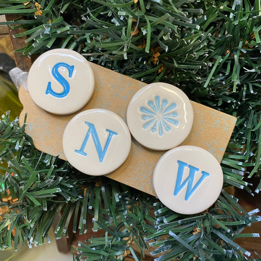 Set of four pottery SNOW magnets on a Christmas gift tag