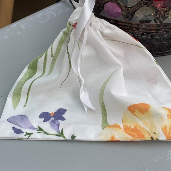 Small handmade floral gift bag with ribbon tie.