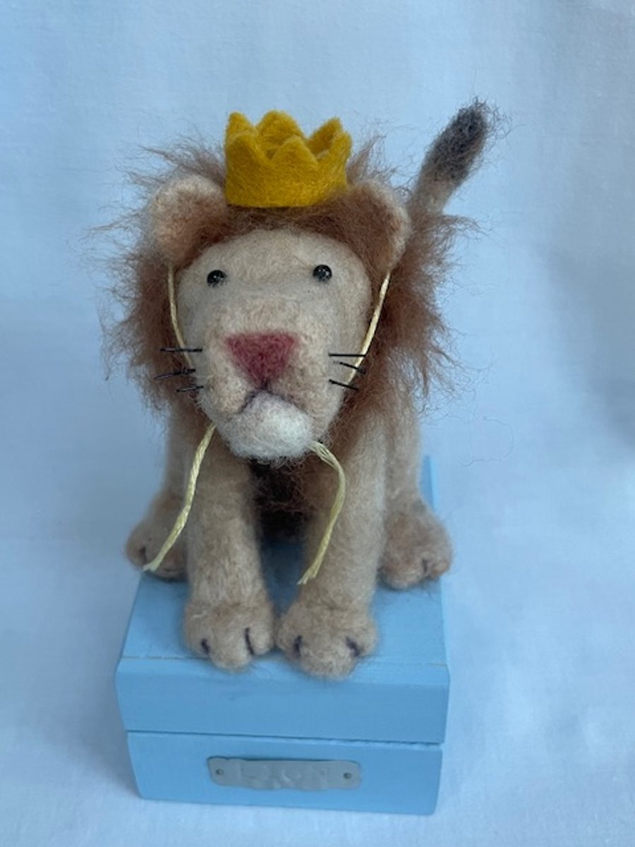 Handcrafted needle felted lion with removable party hat on a wooden box