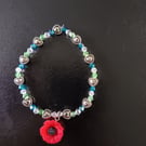 Elasticated poppy charm bracelet with silver and glass beads 