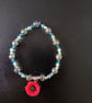 Elasticated poppy charm bracelet with silver and glass beads 