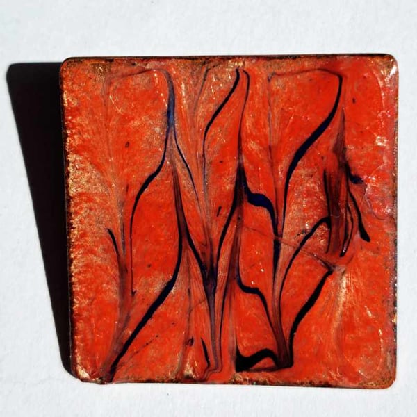 brooch - square: scrolled black and dark blue on red over clear enamel