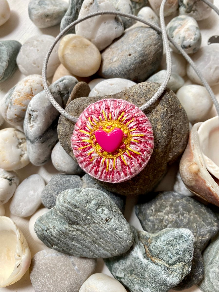 Hand embroidered circular pendant necklace with a tiny pink heart