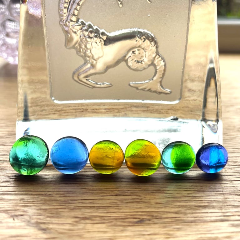 A card of six curious mixed fused glass cabachons, in blues and greens. 