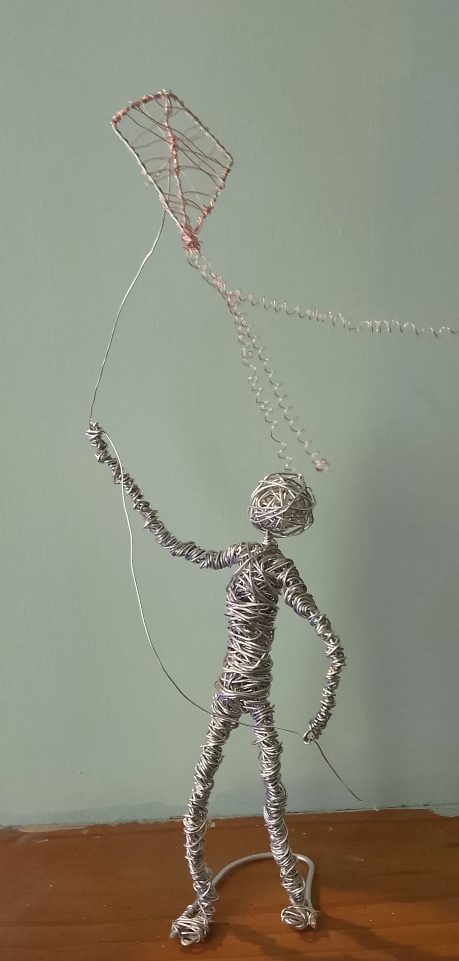 Figure sculptured out of wire flying a kite 