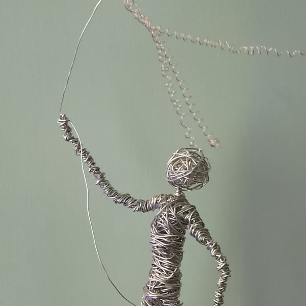 Figure sculptured out of wire flying a kite 