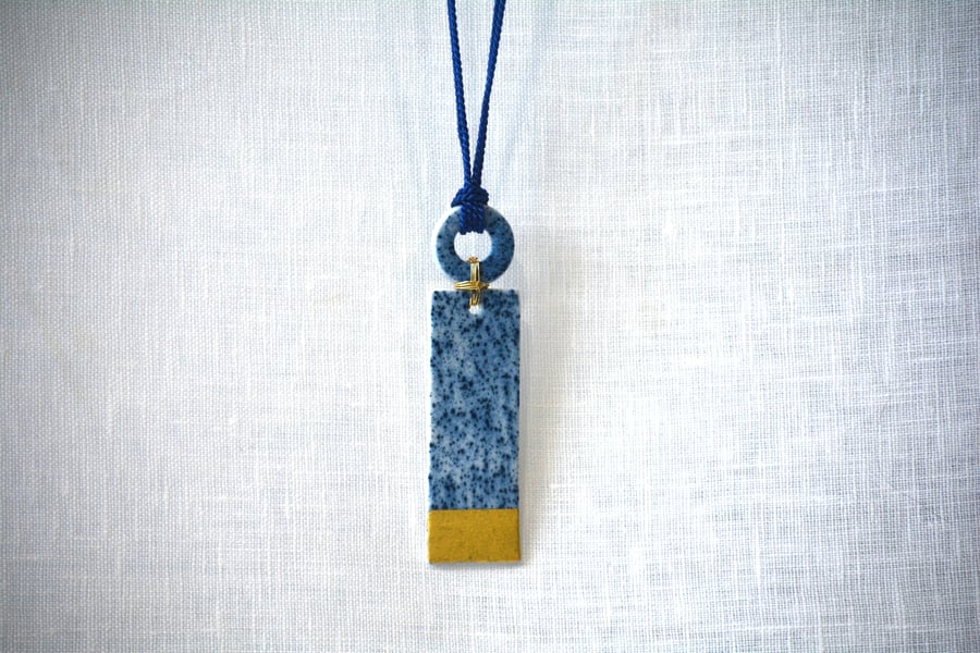 Long porcelain pendant with shapes connected with gold colour plated wire