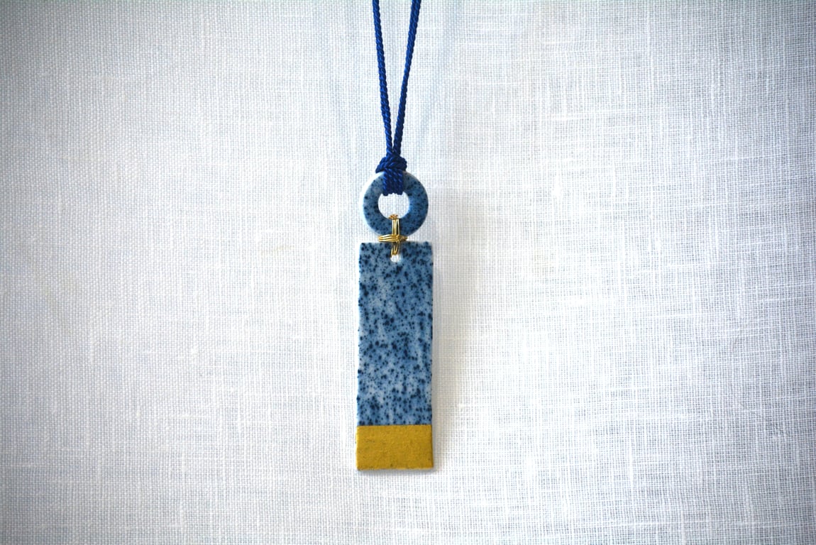 Long porcelain pendant with shapes connected with gold colour plated wire
