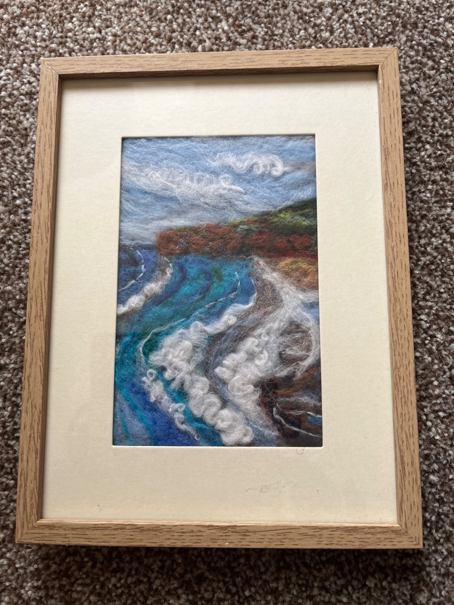 Needle felt coastal beach scene cliffs, waves, cloudy blue sky light wood frame 