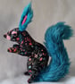 Faux seated floral squirrel with teal tail