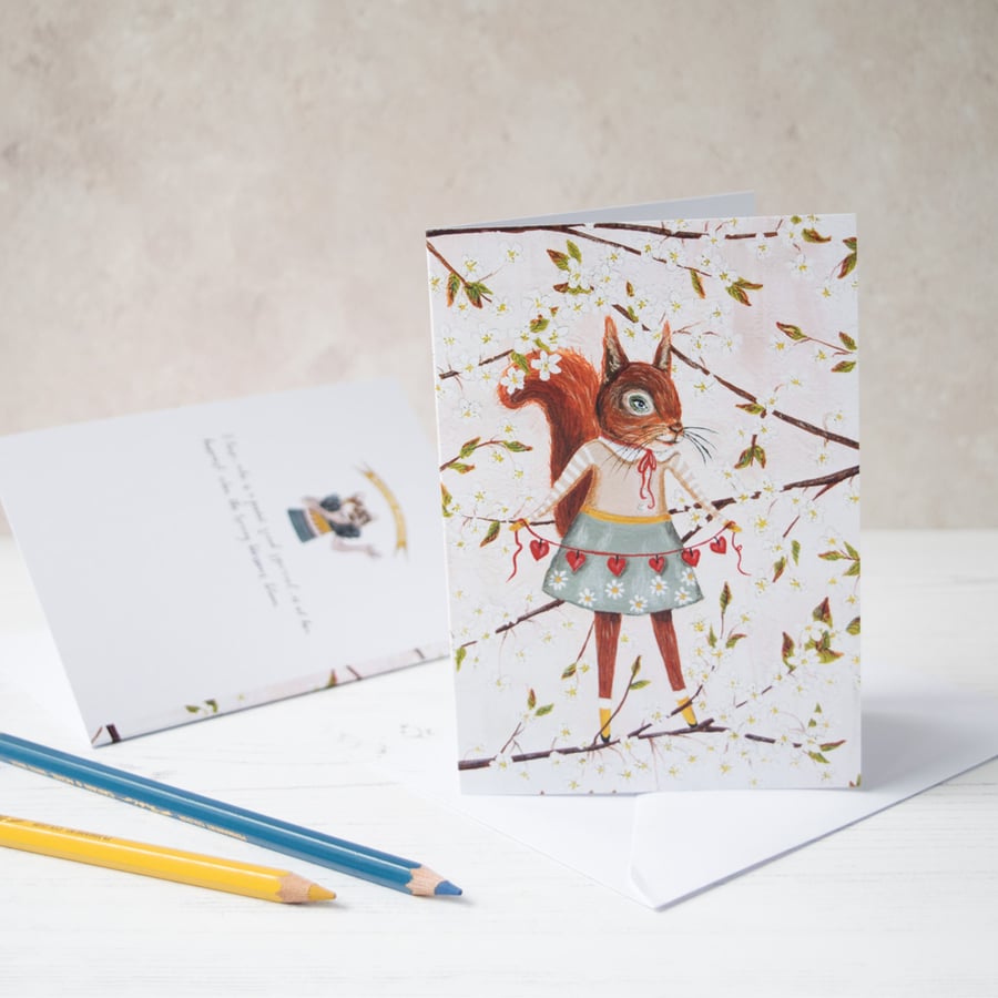 A6 greeting card. Red lady squirrel with chain of hearts amongst blossom flowers
