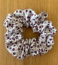 Cotton scrunchie hair accessory in a floral print in white and purple.