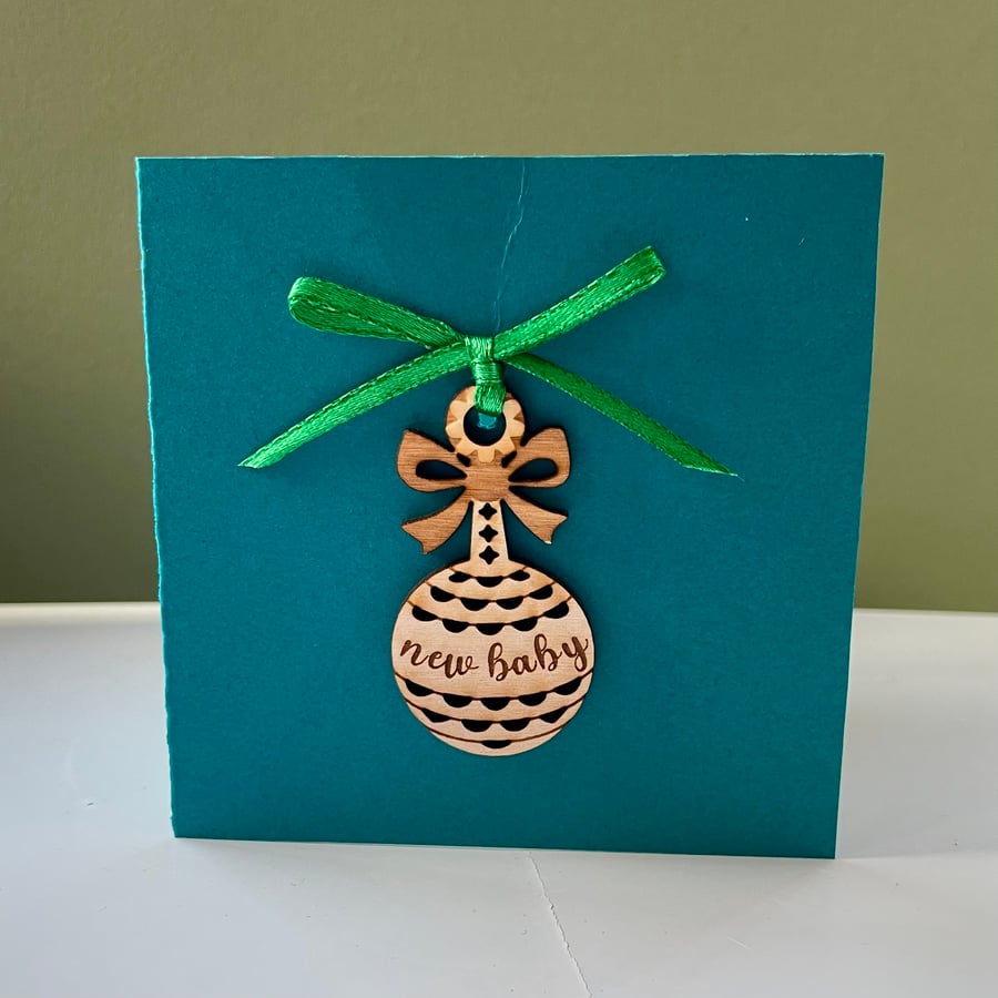 Blank card with detachable wooden 'new baby' rattle decoration