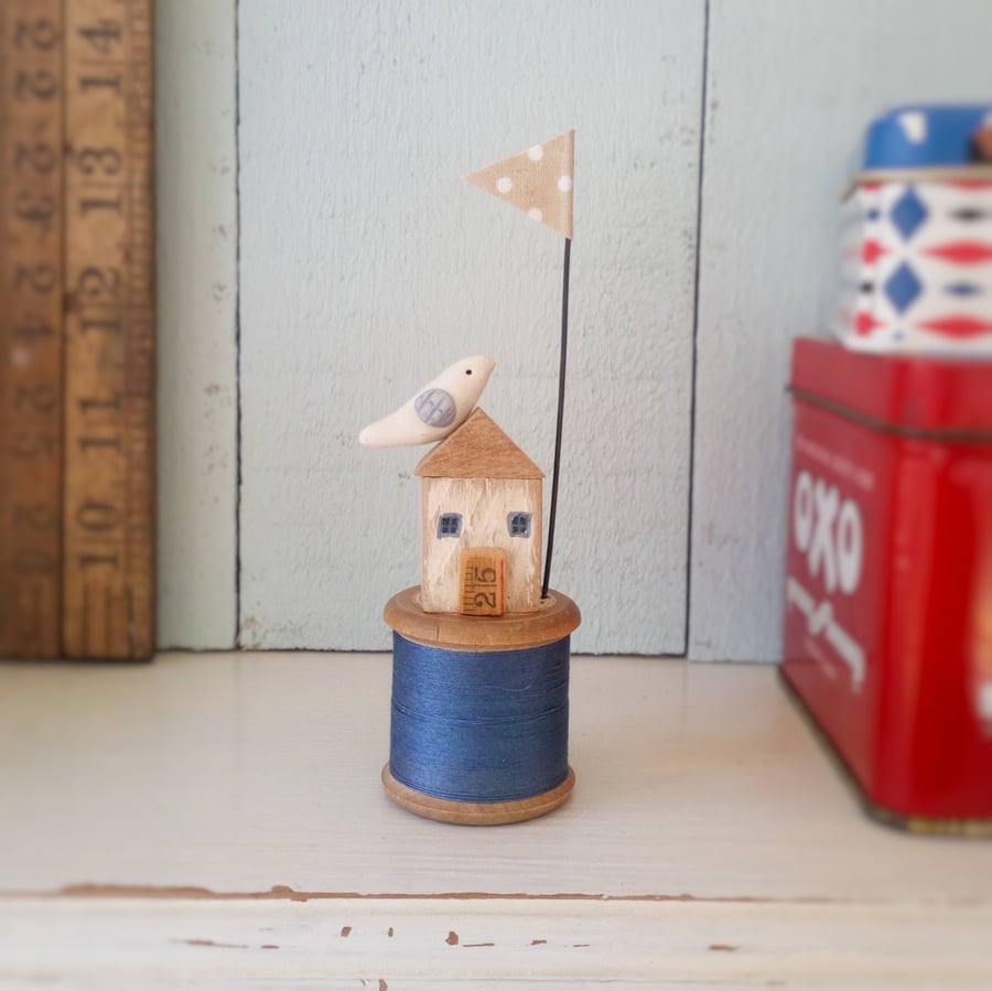 Little oak house with clay seabird on vintage wooden bobbin