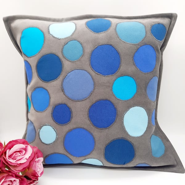 Grey cushion cover with blue circular applique.  