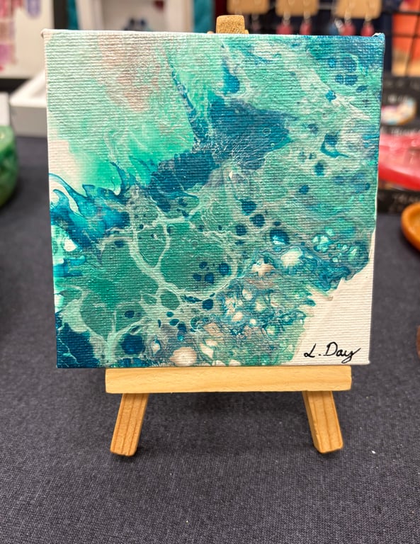 Easel mounted acrylic painted canvas in greens and blues