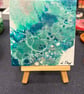 Easel mounted acrylic painted canvas in greens and blues
