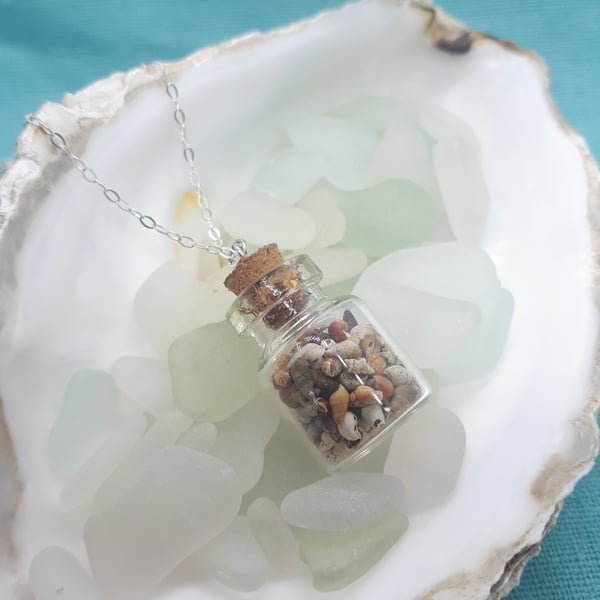 Small glass bottle filled with tiny seashell pendant